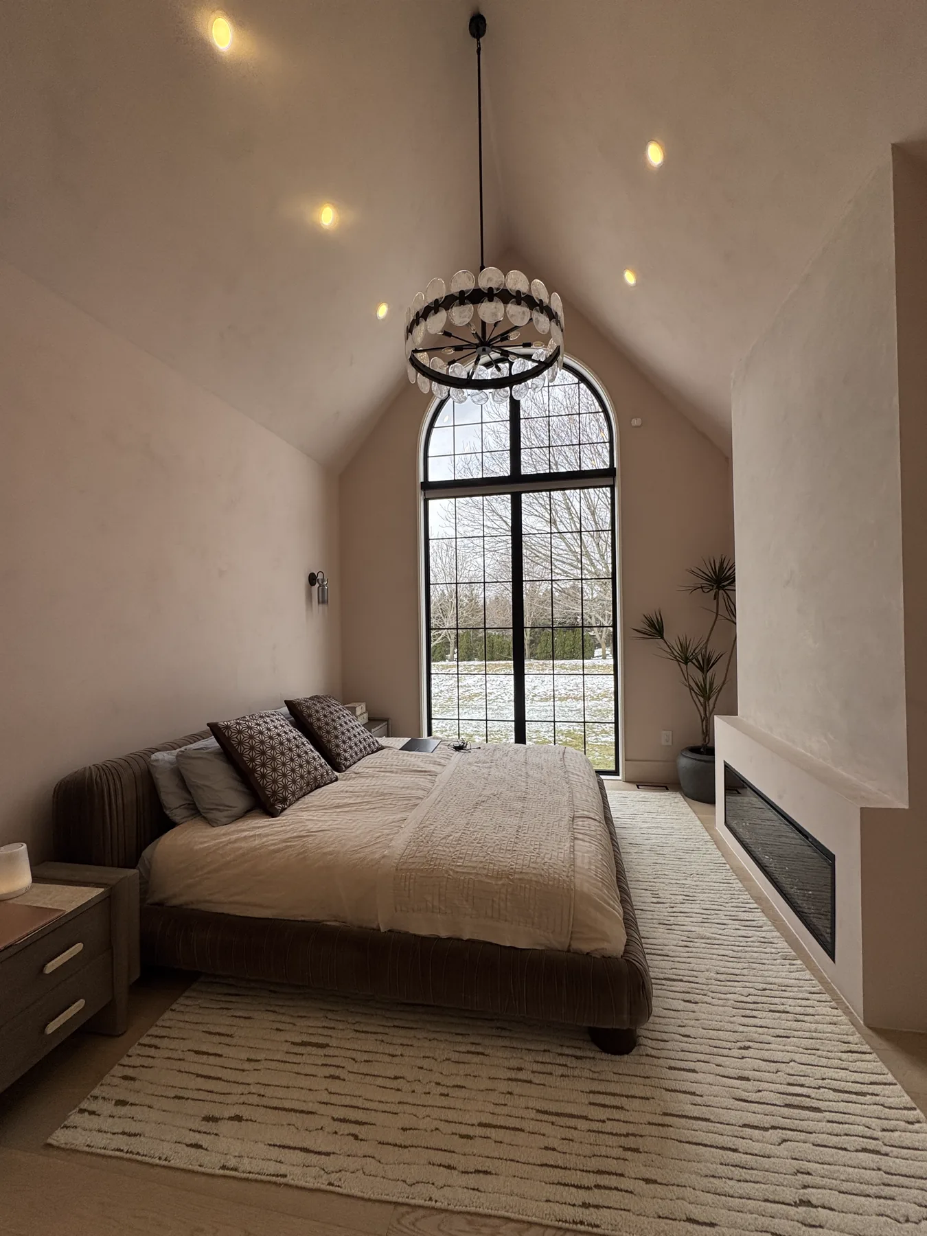 Belsite primary bedroom suite with vaulted ceiling, modern chandelier and fireplace